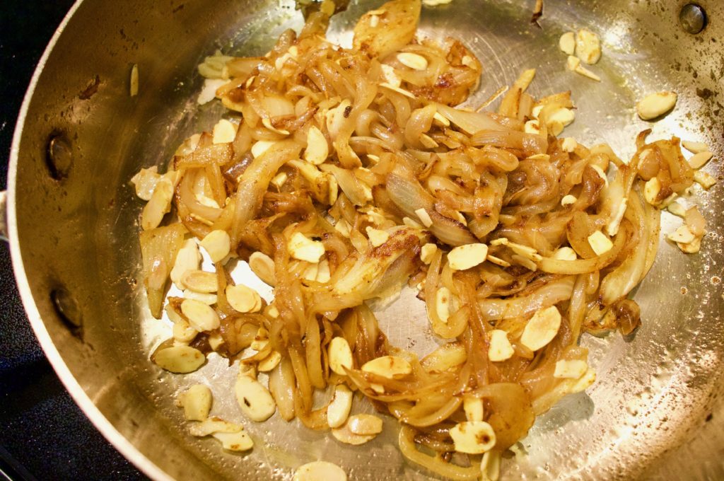Onions with curry powder, spices and almonds in a pan.