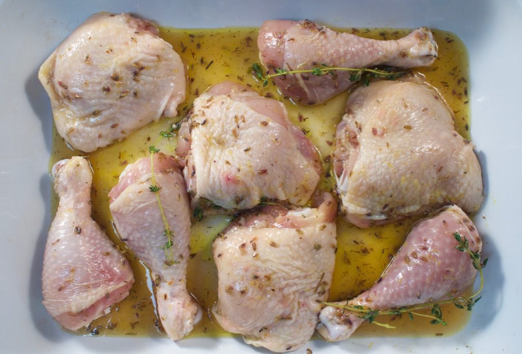 Chicken pieces in pan marinating with lavender, lemon, thyme and honey. 