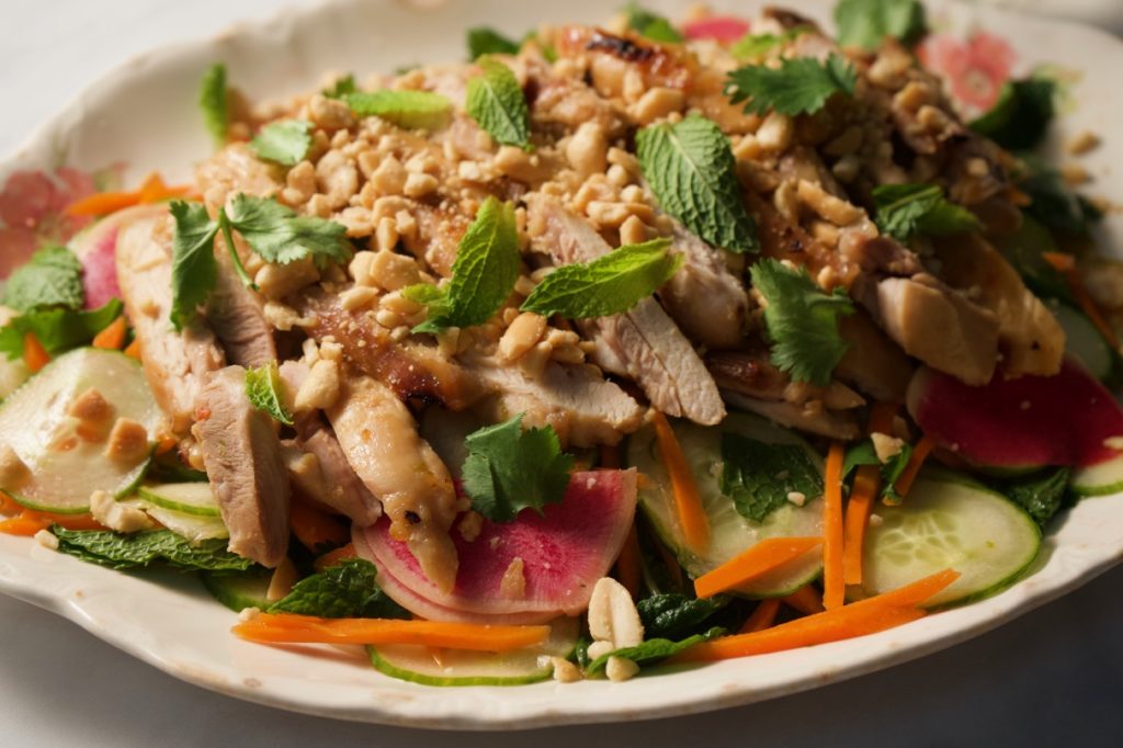 Vietnamese chicken thigh salad with cucumbers, carrots, watermelon radish. Topped with peanuts and herbs.