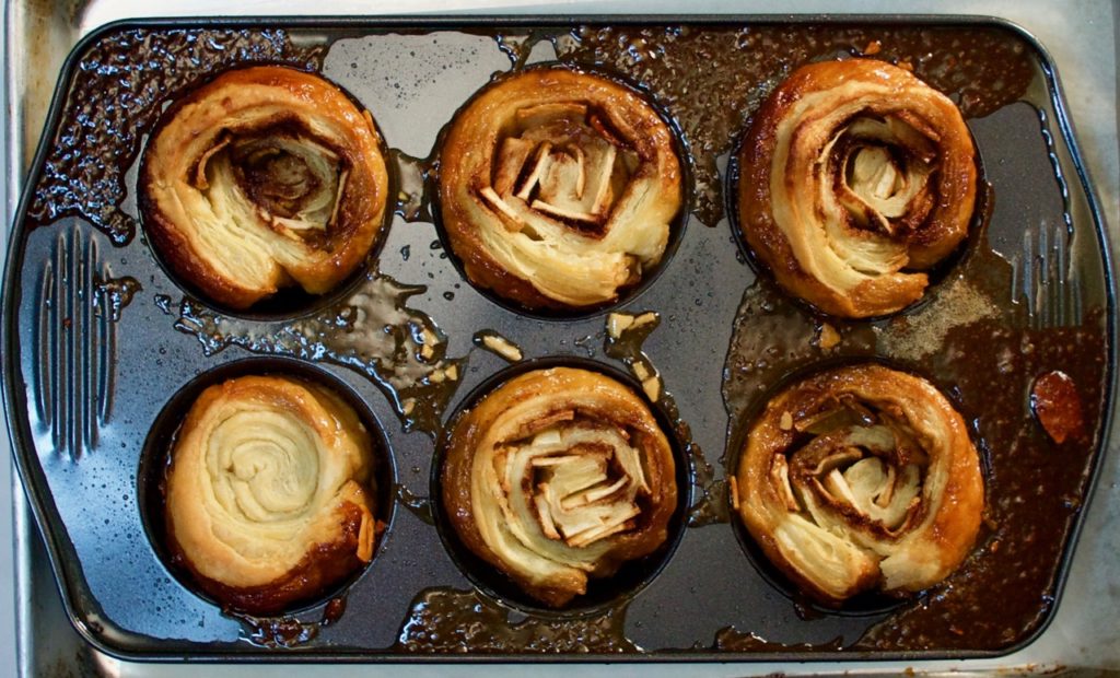 Apple and cinnamon filled sticky buns hot from the oven. Make these easy buns with store bought puff pastry for a special breakfast treat anytime!