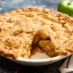 Apple pie with one slice cut out. Apple and striped towel.