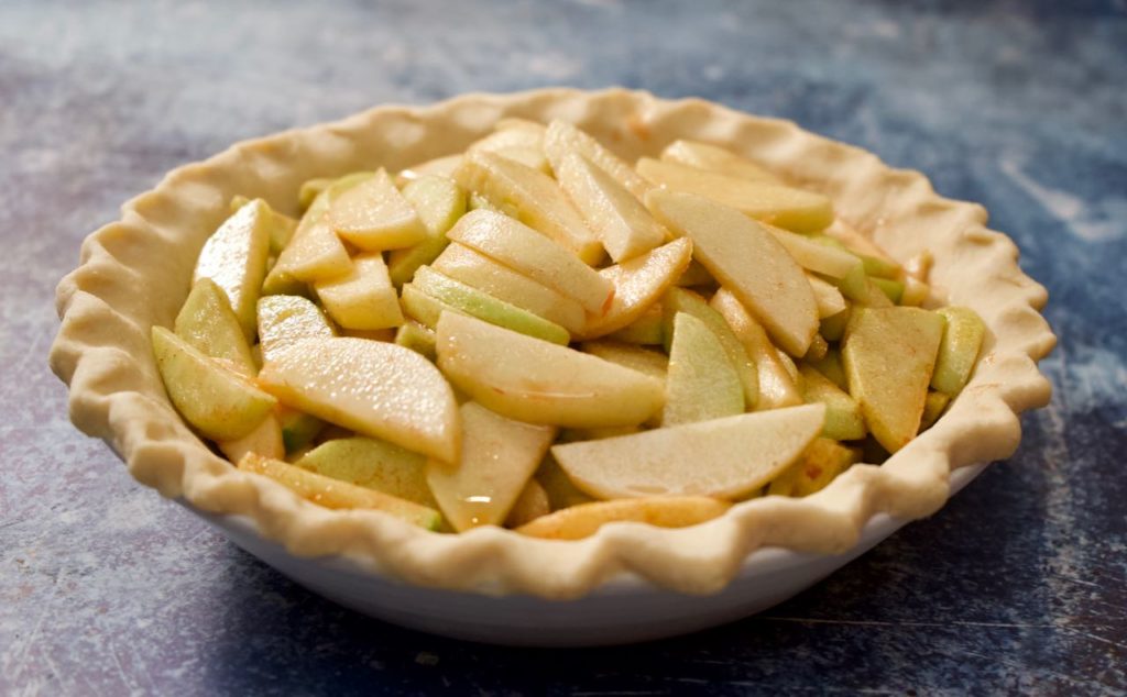 Apples sliced in uncooked pie crust. 