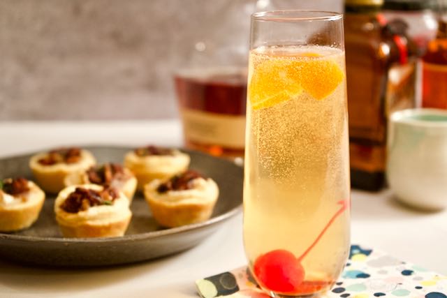 champagne glass filled with cocktail, plate full of tartlets