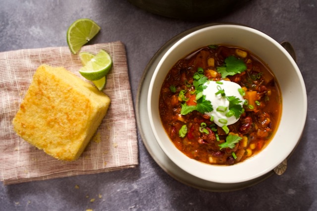 Cornbread, limes and bowl of butternut squash and bean chili.