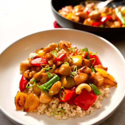 Chicken cashew stir fry over rice in a bowl.