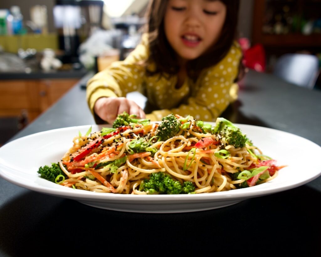 Platter of cold sesame noodles in front of child.
