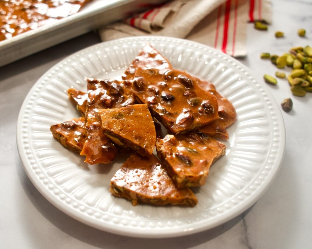 Pistachio brittle on plate with towel and nuts.