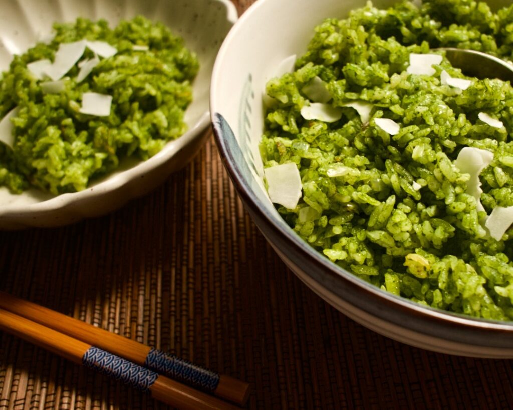 Two bowls of green coconut rice on placemat with chopsticks.