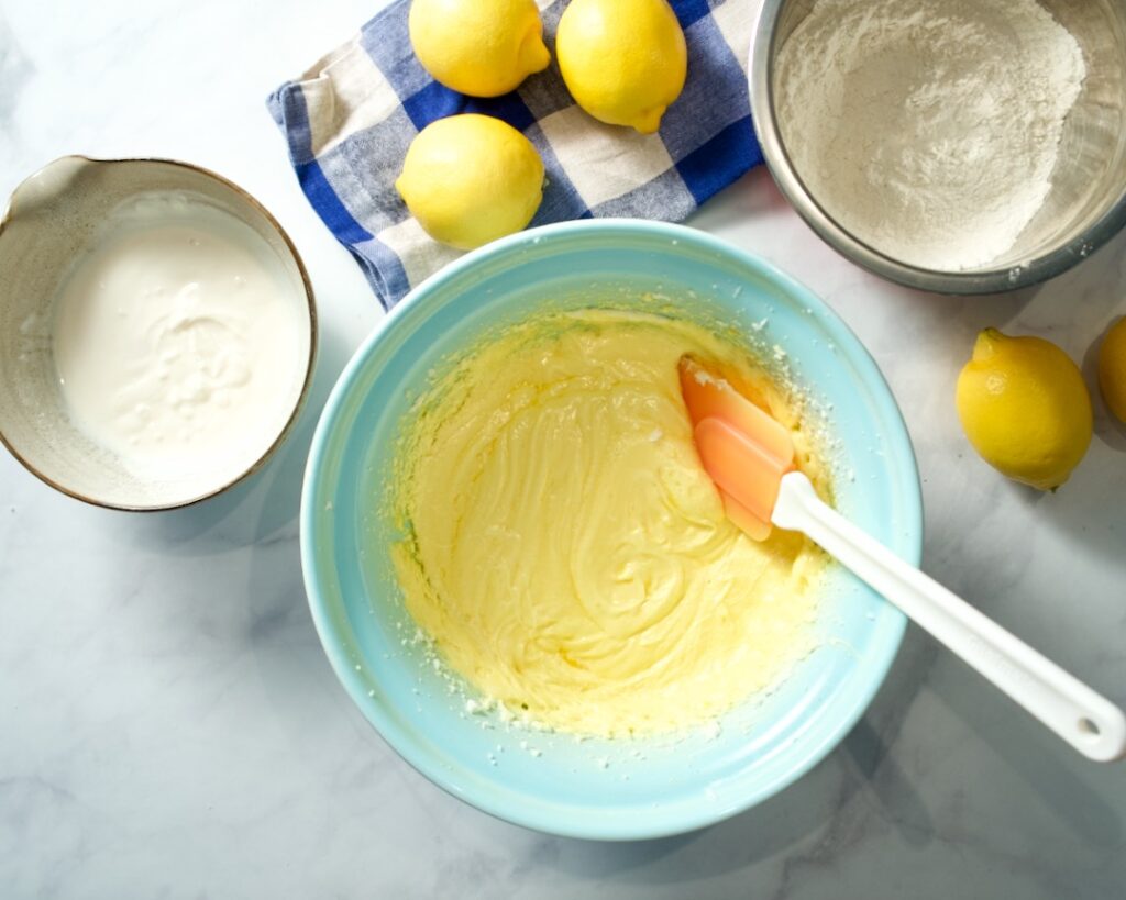 Bowl of batter, wet ingredients and dry ingredients. Lemons on a towel.