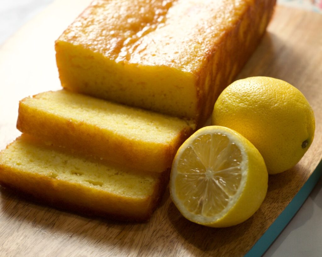Sliced pound cake on board with lemons.