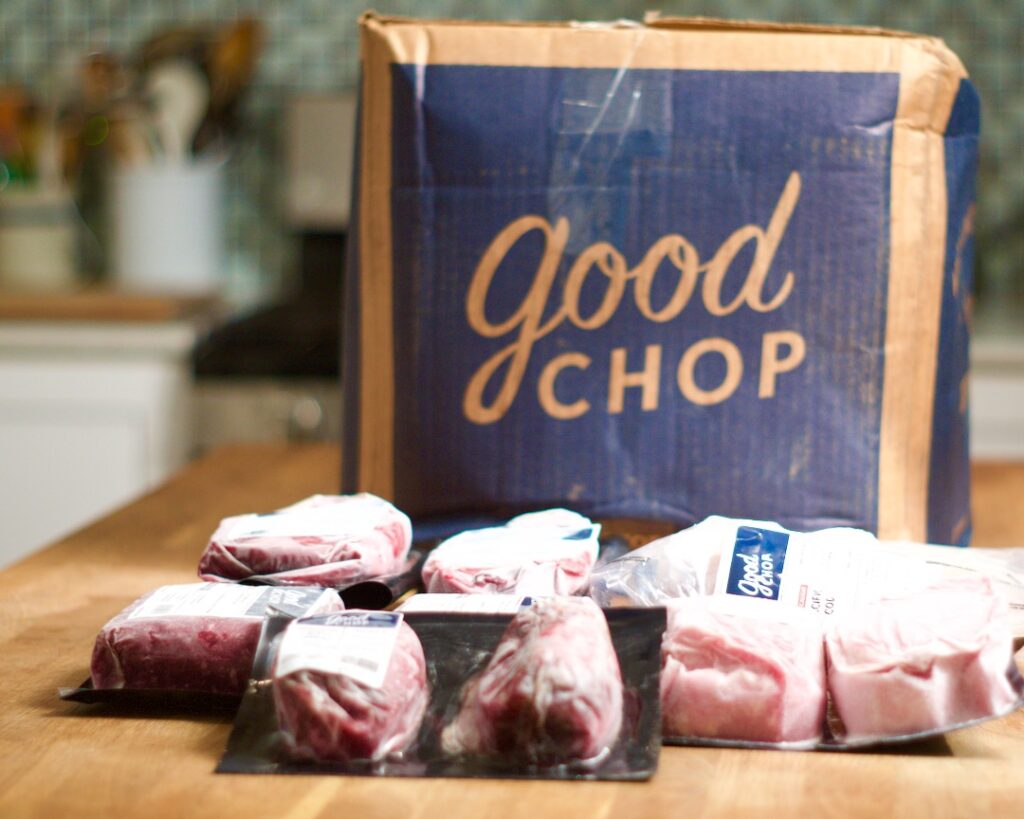 Frozen pieces of meat with cardboard box behind them with "Good Chop" logo.
